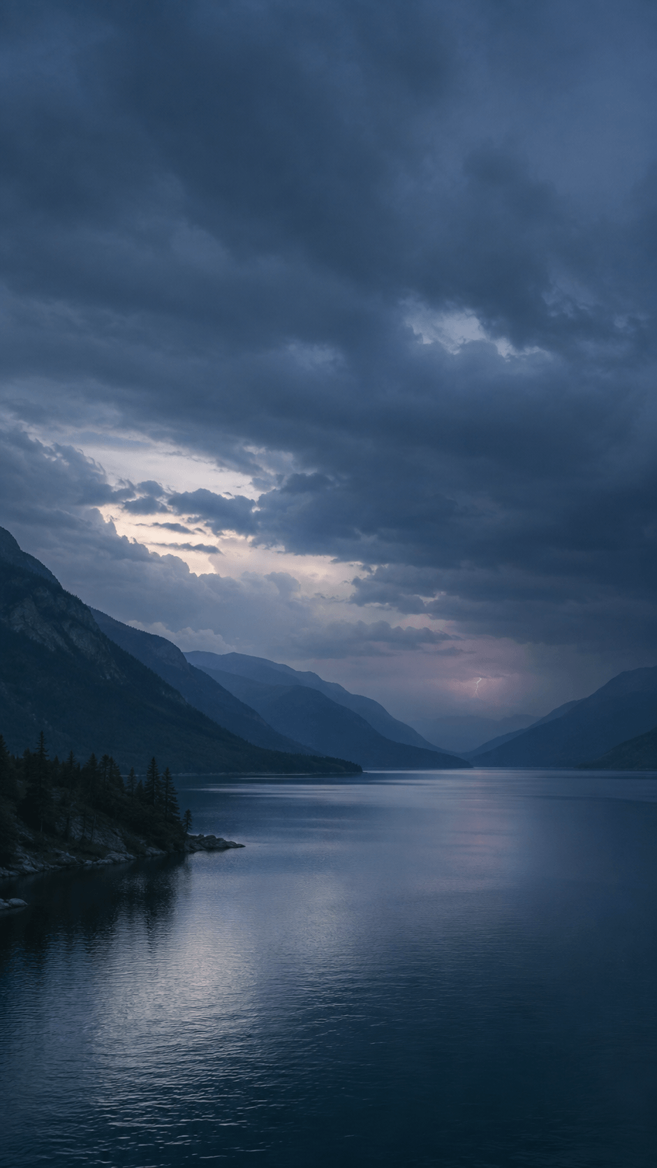 Distant lightning over a dark mountain valley beneath storm clouds