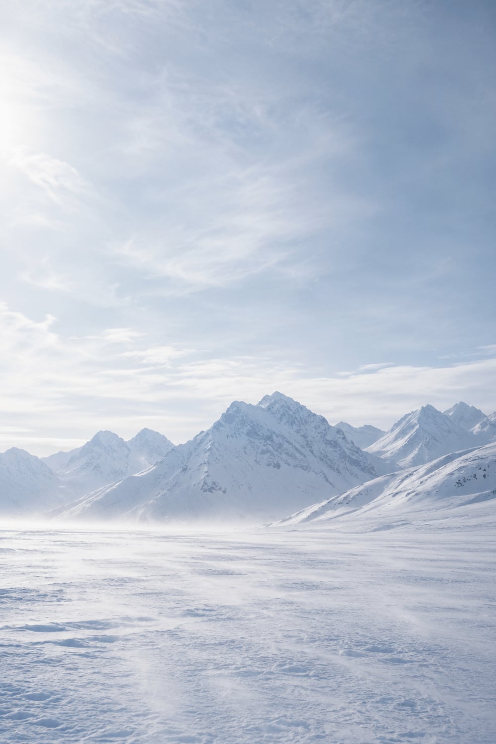 Pale winter light over a wide snowy mountain valley